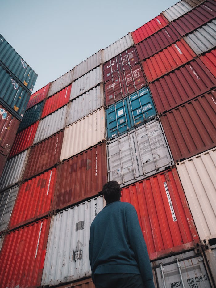 Man in Black Jacket Standing in Front of Red and Blue Building